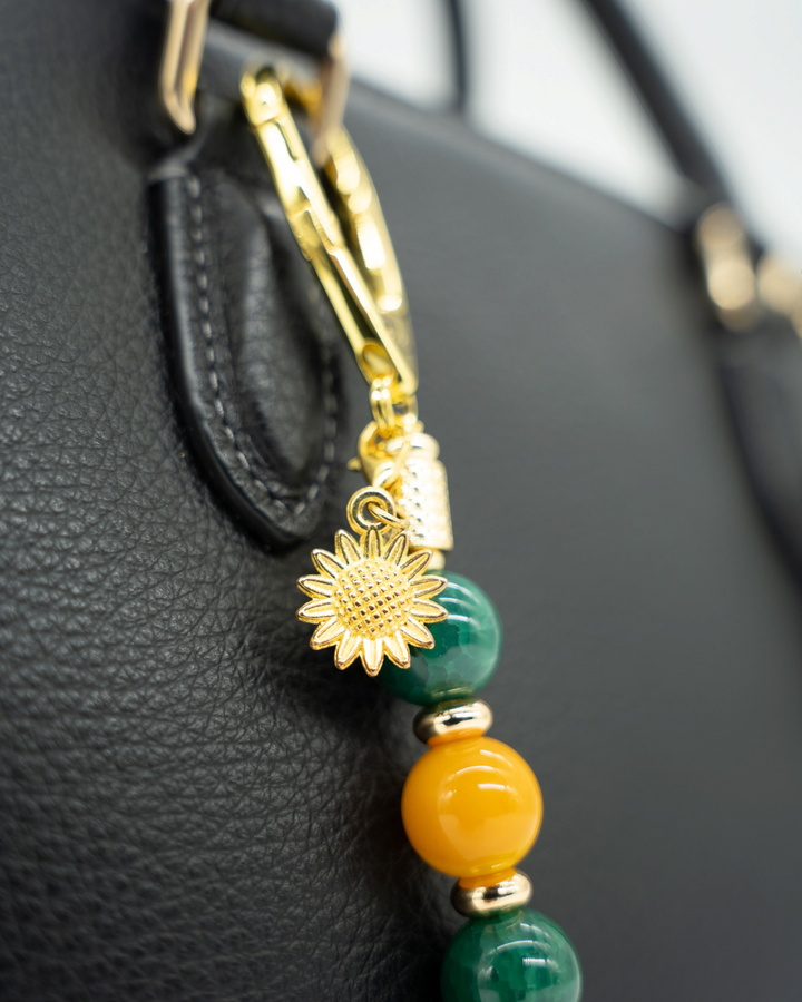 LD Keyfinder Golden Harvest-Mini featuring green and orange agate beads with a gold-plated sunflower charm on a bag