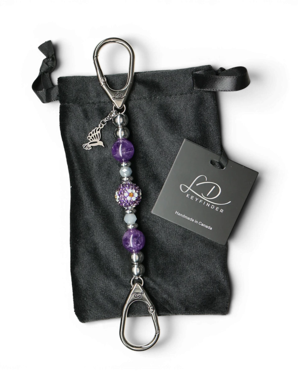 LD Keyfinder Hummingbird Dream Mini keychain with amethyst, crystal daisy bead, and hummingbird charm on black velvet bag.