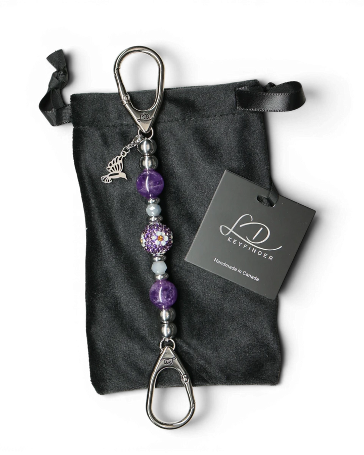 LD Keyfinder Hummingbird Dream Mini keychain with amethyst, crystal daisy bead, and hummingbird charm on black velvet bag.