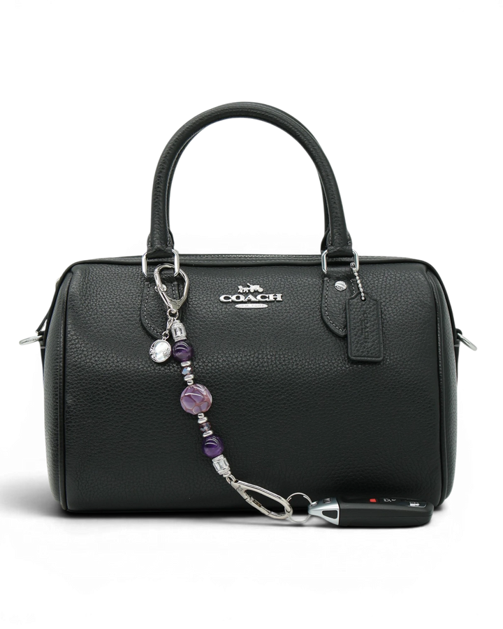 LD Keyfinder Petite Amethyst Moon charm with purple beads, rhinestones, and moon charm on a black handbag.