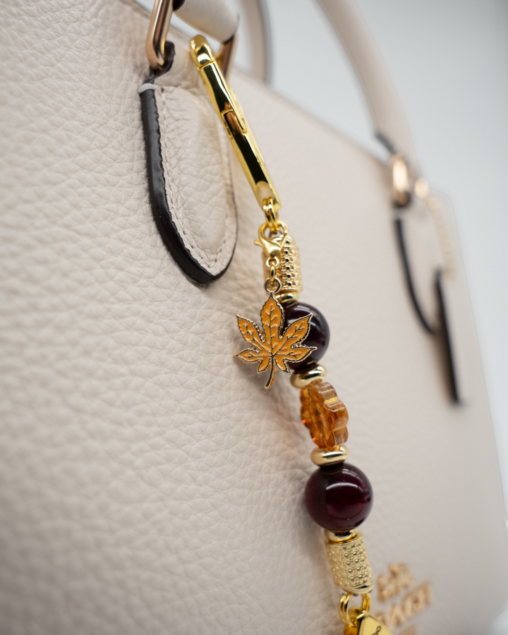 LD Keyfinder Hello Autumn-Mini featuring burgundy agate beads, amber glass flower, and gold maple leaf charm on a bag