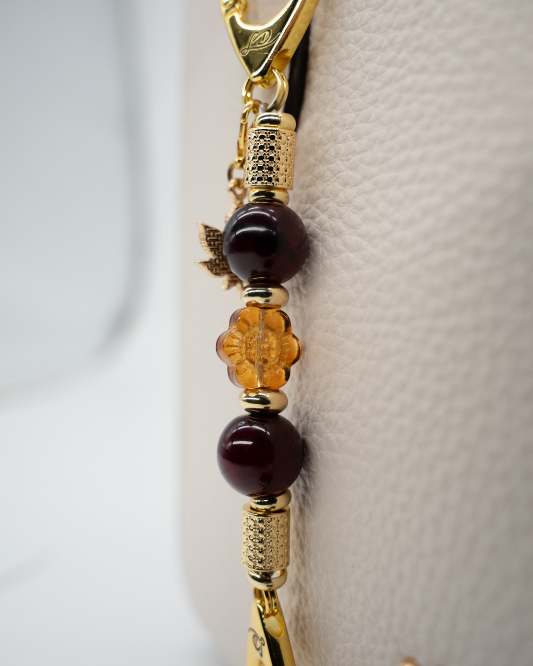 LD Keyfinder Hello Autumn-Mini featuring burgundy agate, amber glass flower, and gold maple leaf charm on a bag.