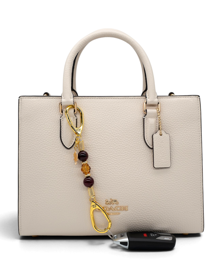 LD Keyfinder Hello Autumn-Mini beaded keychain with burgundy agate and glass flower charm attached to a cream handbag
