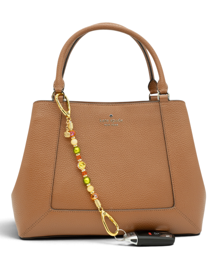 LD Keyfinder Autumn Festival beaded accessory with flower and pumpkin charms attached to a brown leather handbag.