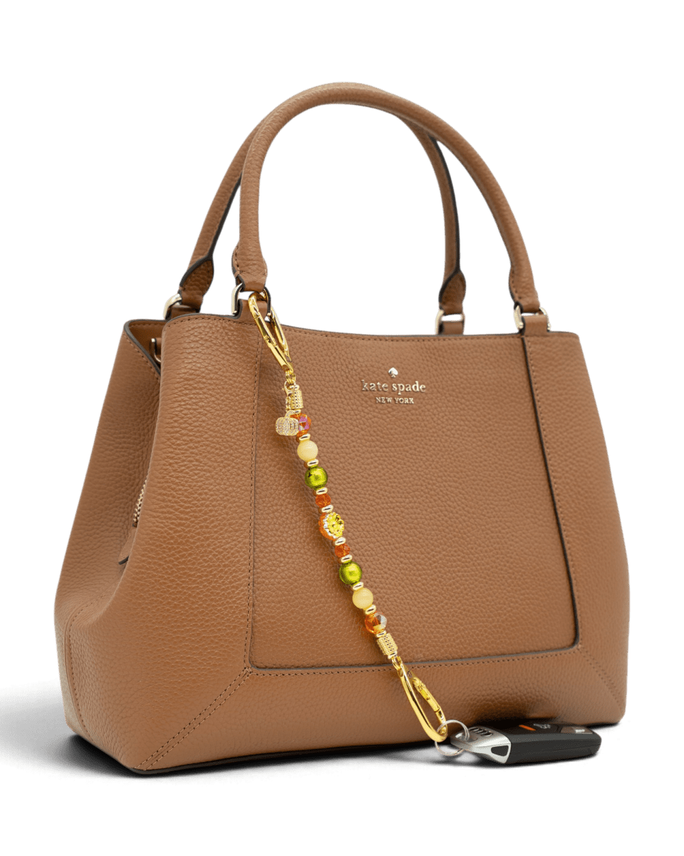 LD Keyfinder Autumn Festival beaded accessory with flower and pumpkin charms attached to a brown leather handbag