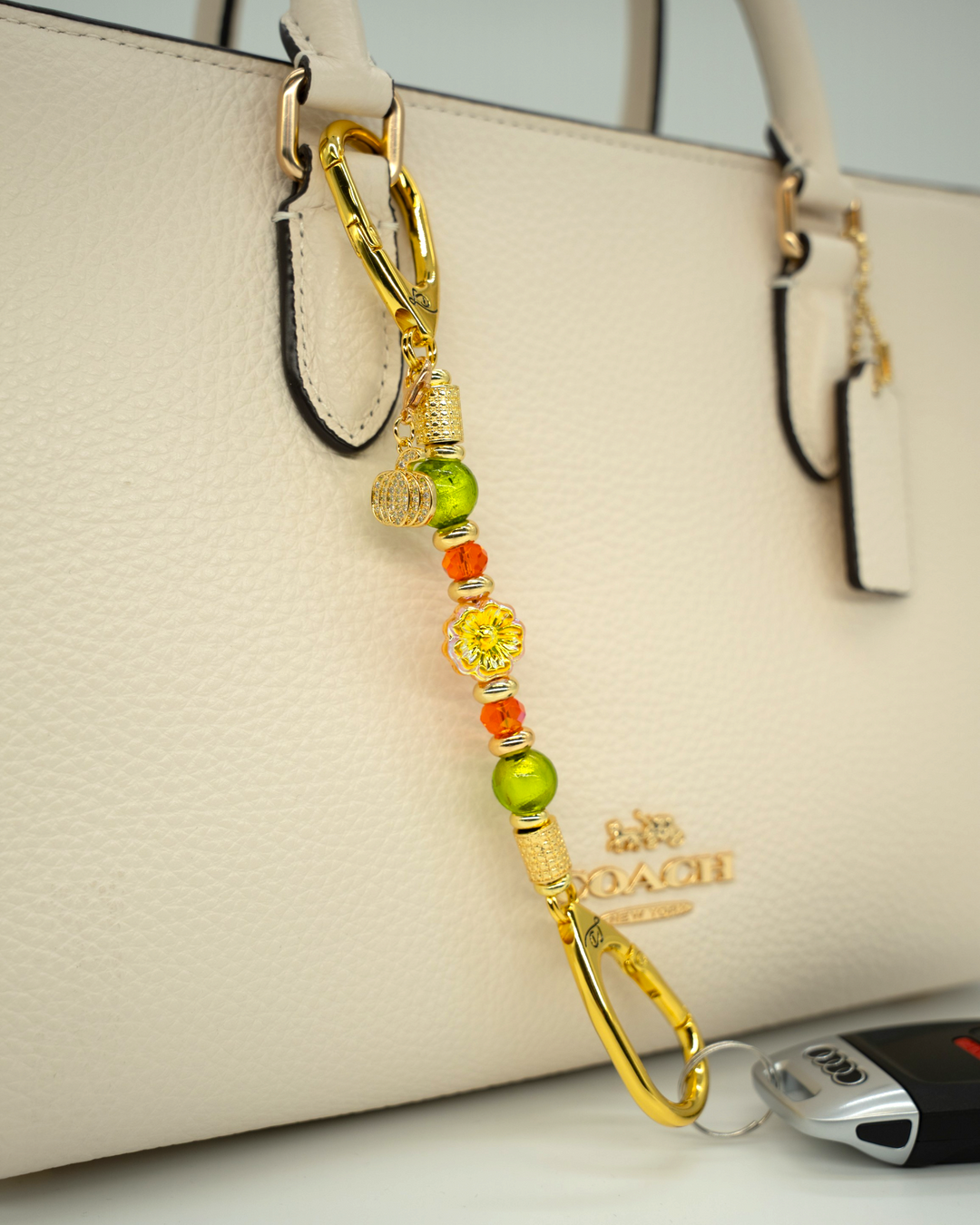 LD Keyfinder Autumn Festival-Mini featuring green foil beads, orange glass beads, gold flower, and pumpkin charm.