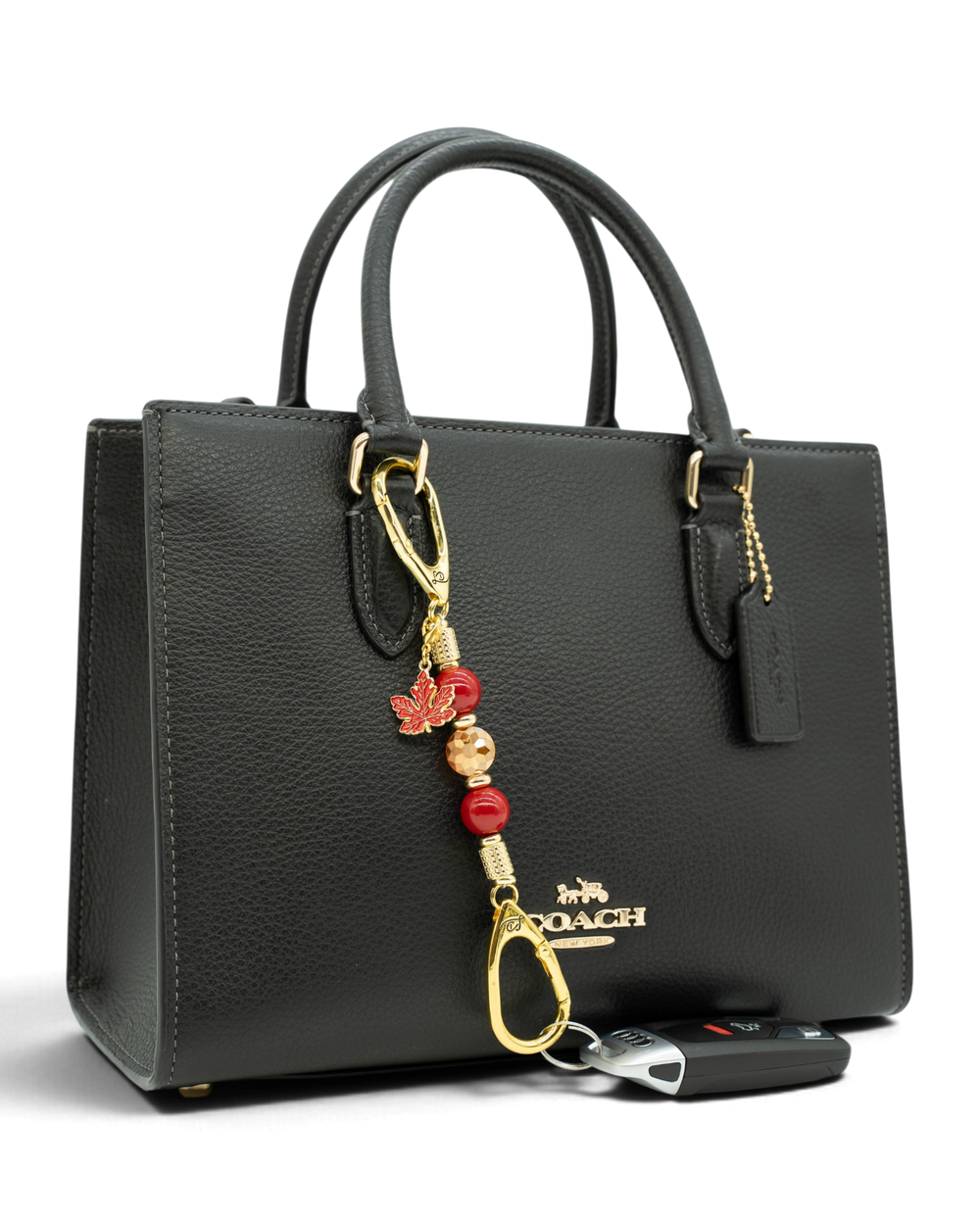 LD Keyfinder Autumn Glow-Mini beaded charm with red shell pearls and maple leaf attached to a black leather handbag.