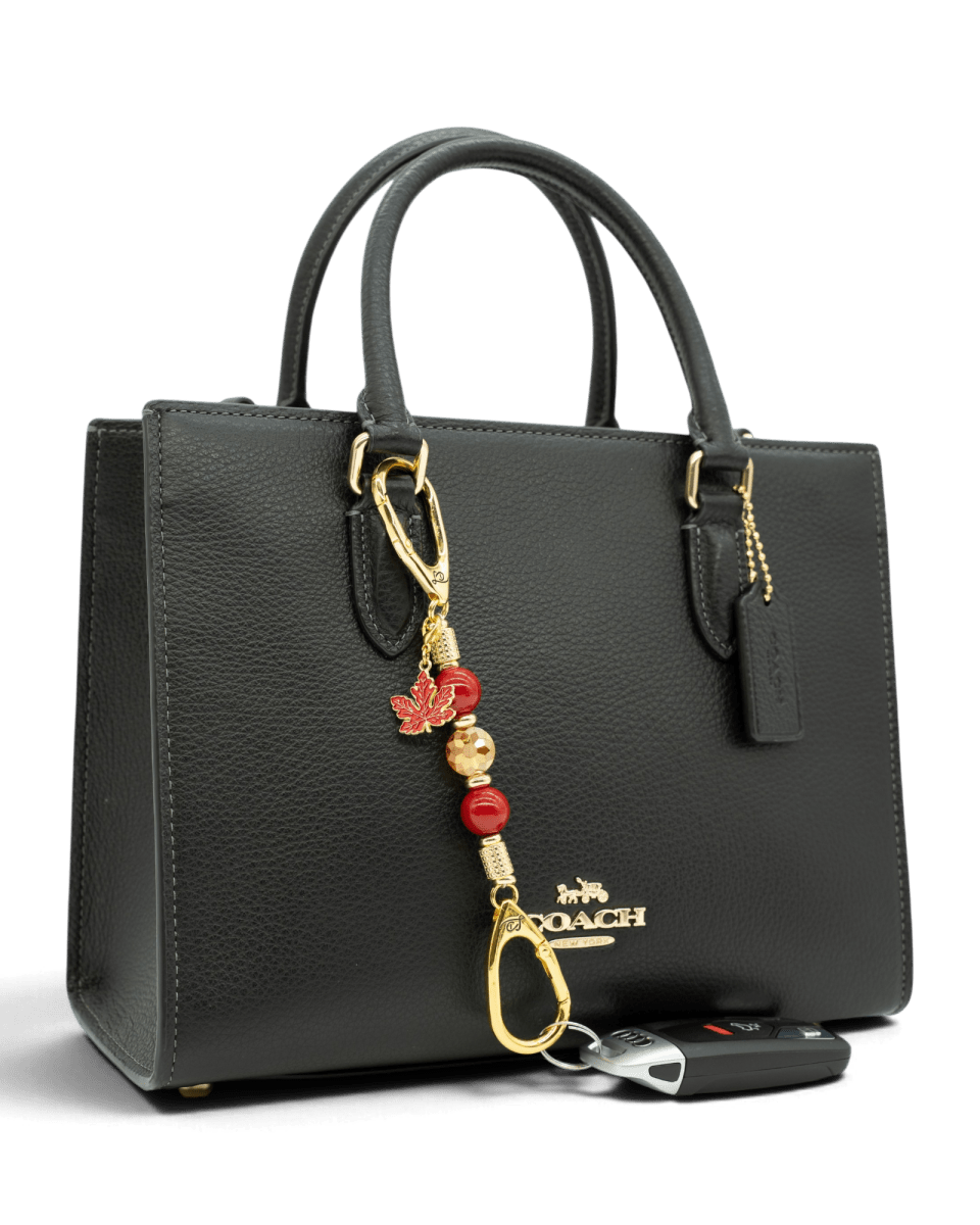 LD Keyfinder Autumn Glow-Mini beaded charm with red shell pearls and maple leaf attached to a black leather handbag.