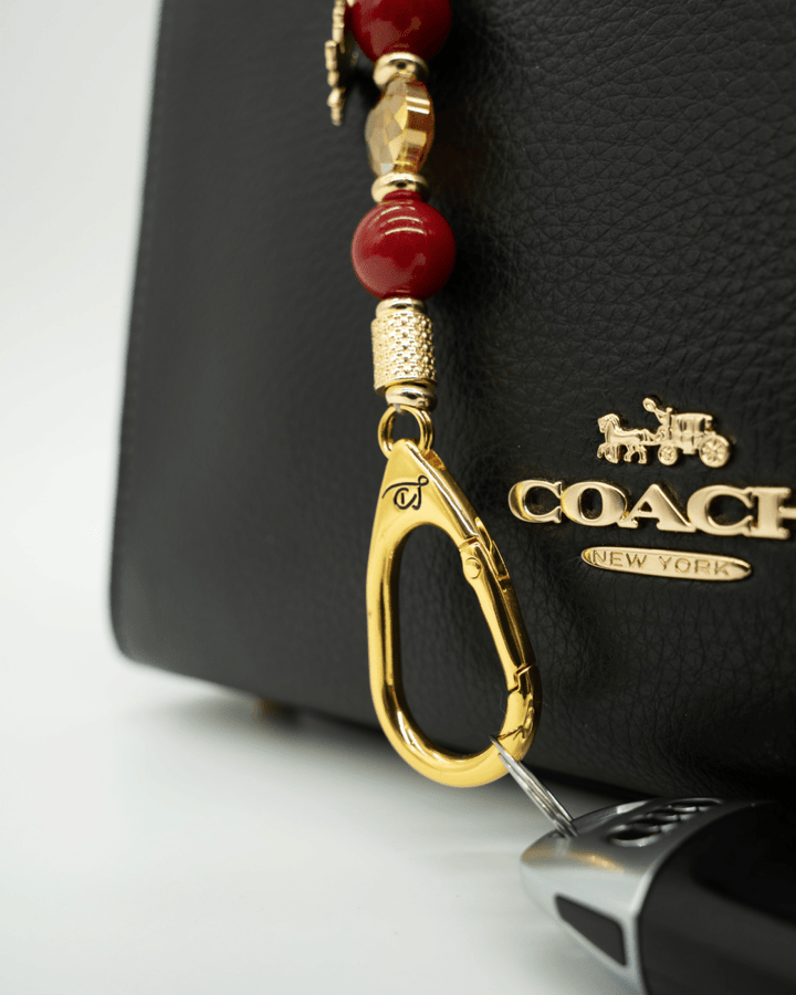 LD Keyfinder Autumn Glow-Mini featuring red shell pearls, amber glass bead, and gold maple leaf charm on a black bag
