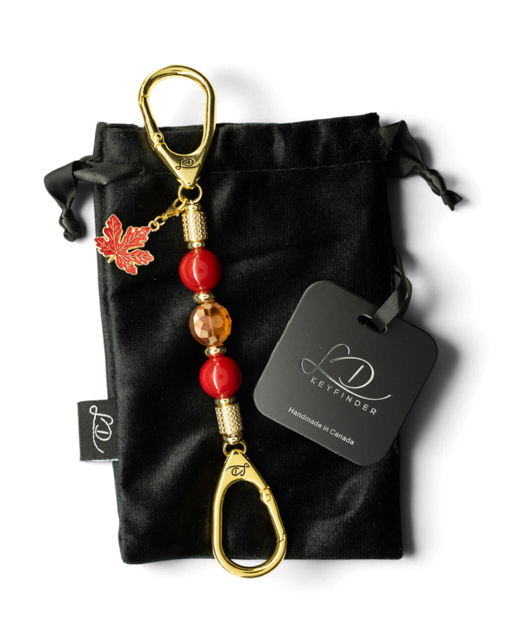 LD Keyfinder Autumn Glow-Mini keychain with red shell pearls, amber glass bead, gold maple leaf charm, and velvet bag.