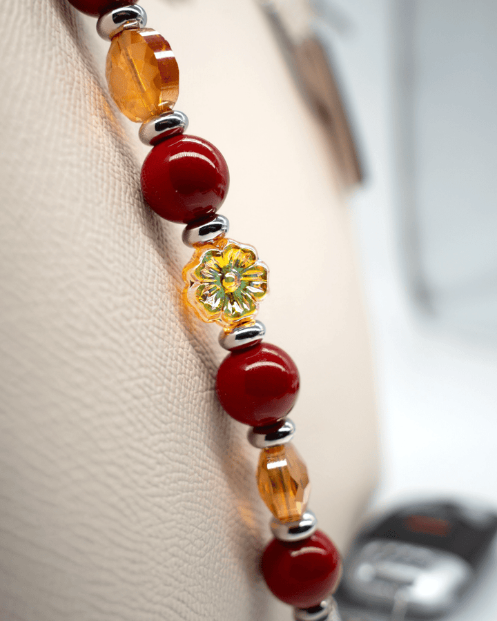 LD Keyfinder Autumn Whispers beaded accessory featuring red shell pearls, orange glass flowers, and platinum-plated charms.