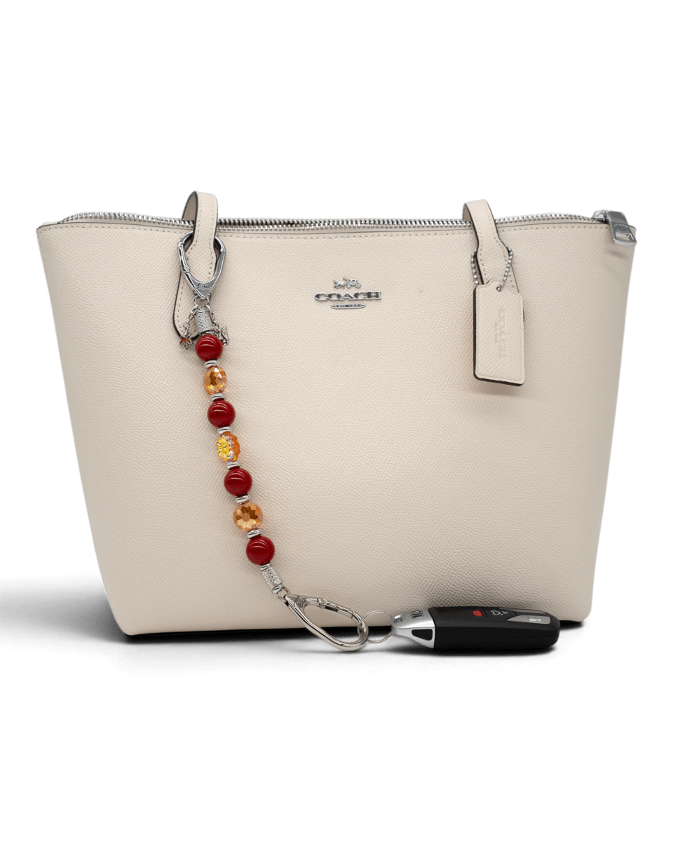 LD Keyfinder Autumn Whispers beaded accessory with red pearls, orange glass flowers, and charms attached to a handbag.