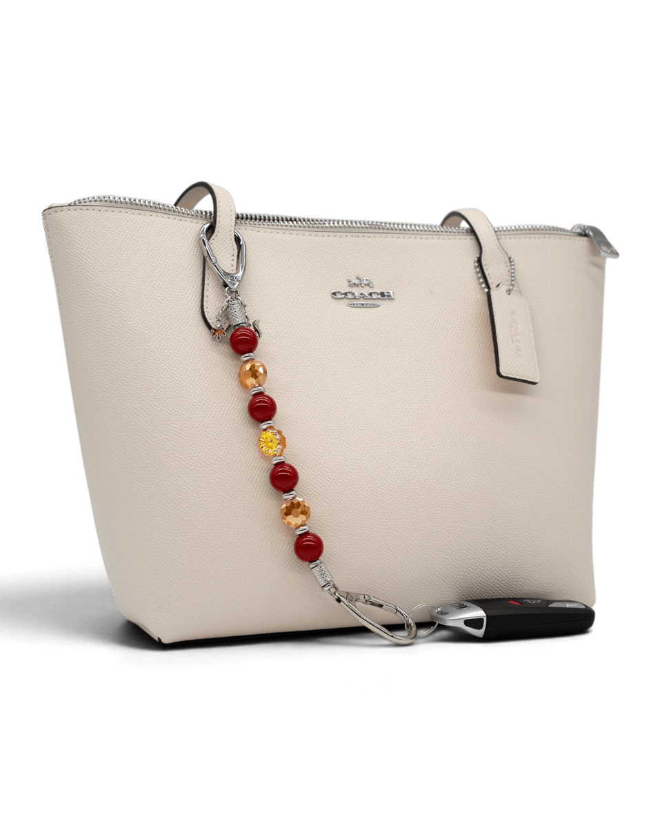 LD Keyfinder Autumn Whispers beaded key finder with red shell pearls and orange glass flower attached to a beige bag.