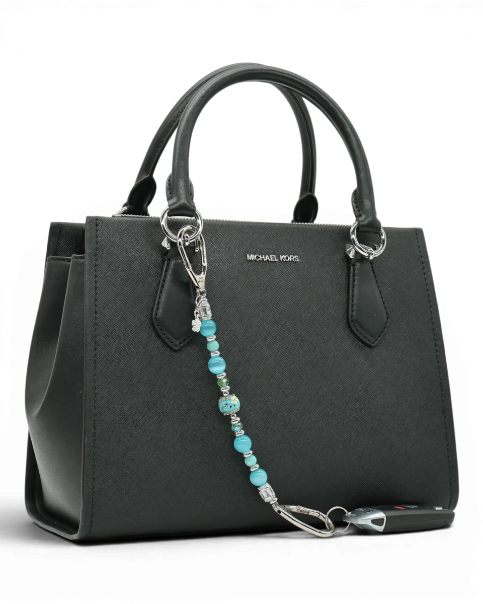 LD Keyfinder Azure Meadow beaded charm with aqua blue, green, and white daisy lampwork glass beads on a black handbag.