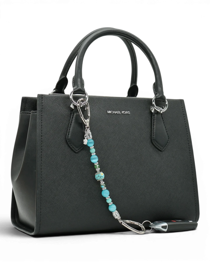 LD Keyfinder Azure Meadow beaded charm with aqua blue, green, and white daisy lampwork glass beads on a black handbag.