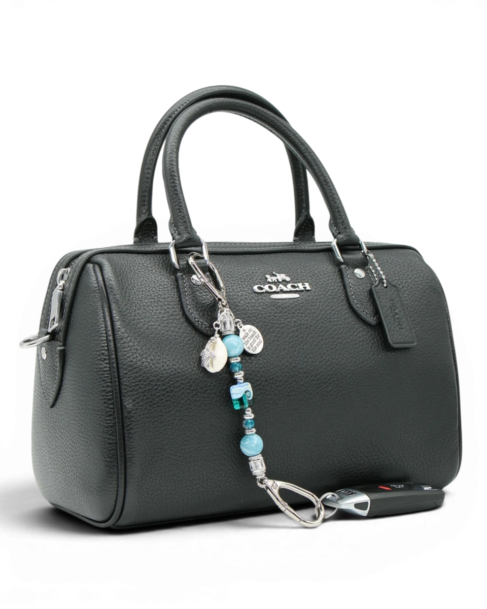 LD Keyfinder Petite Beachy Dreams charm with blue and teal beads, turtle charm, and inspirational quote charm attached to a black handbag.