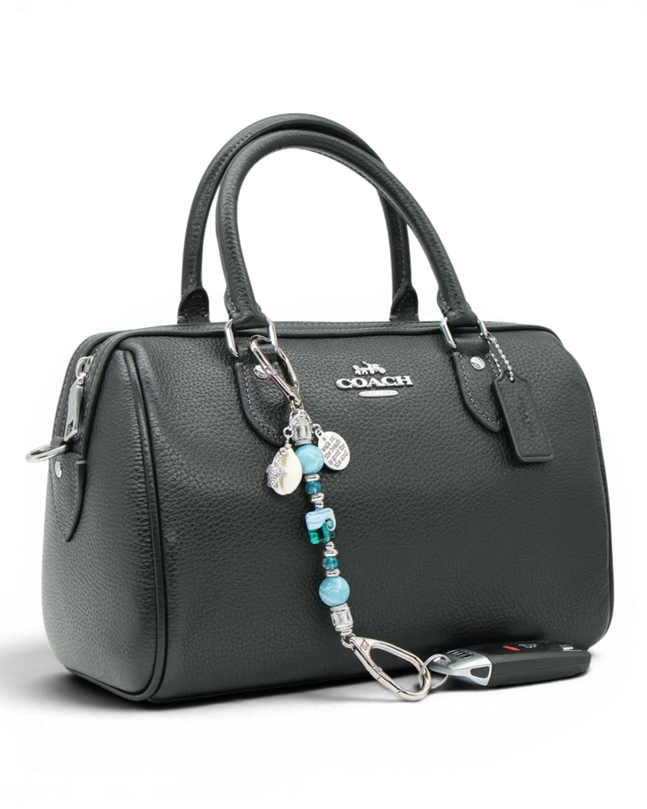 LD Keyfinder Petite Beachy Dreams charm with blue and teal beads, turtle charm, and inspirational quote charm attached to a black handbag.