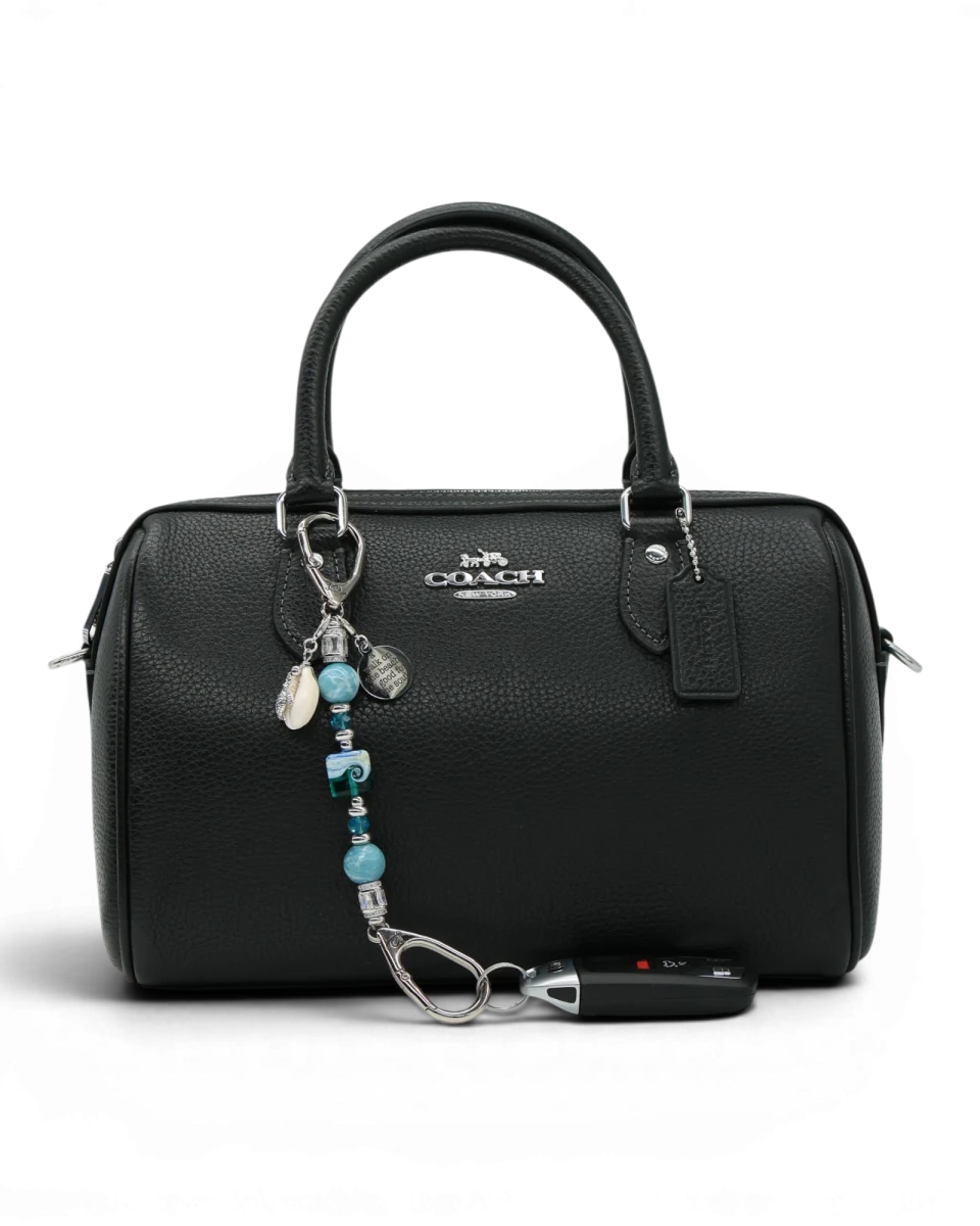 LD Keyfinder Petite Beachy Dreams charm with blue and teal beads, a turtle charm, and a shell charm attached to a black handbag.
