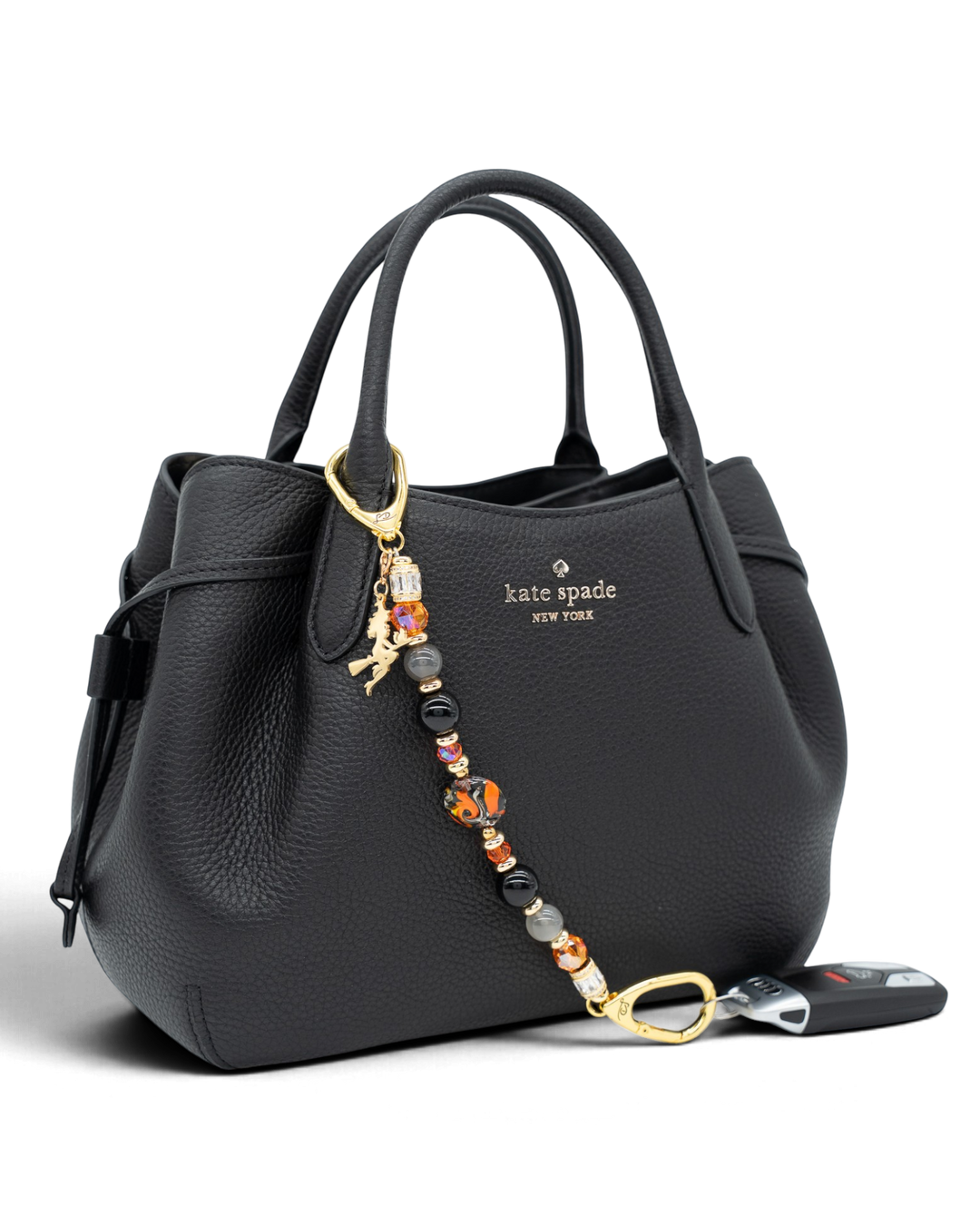 LD Keyfinder Bewitched Halloween accessory with obsidian, moonstone, and orange glass beads on a black leather handbag.