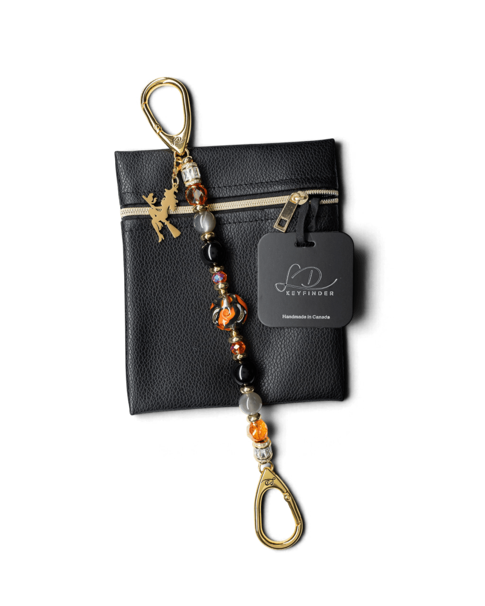 LD Keyfinder Bewitched Halloween accessory with obsidian, moonstone, orange glass beads, and a gold witch charm on a pouch.