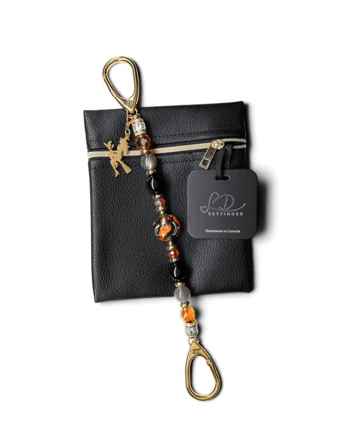 LD Keyfinder Bewitched Halloween accessory with obsidian, moonstone, orange glass beads, and a gold witch charm on a pouch.