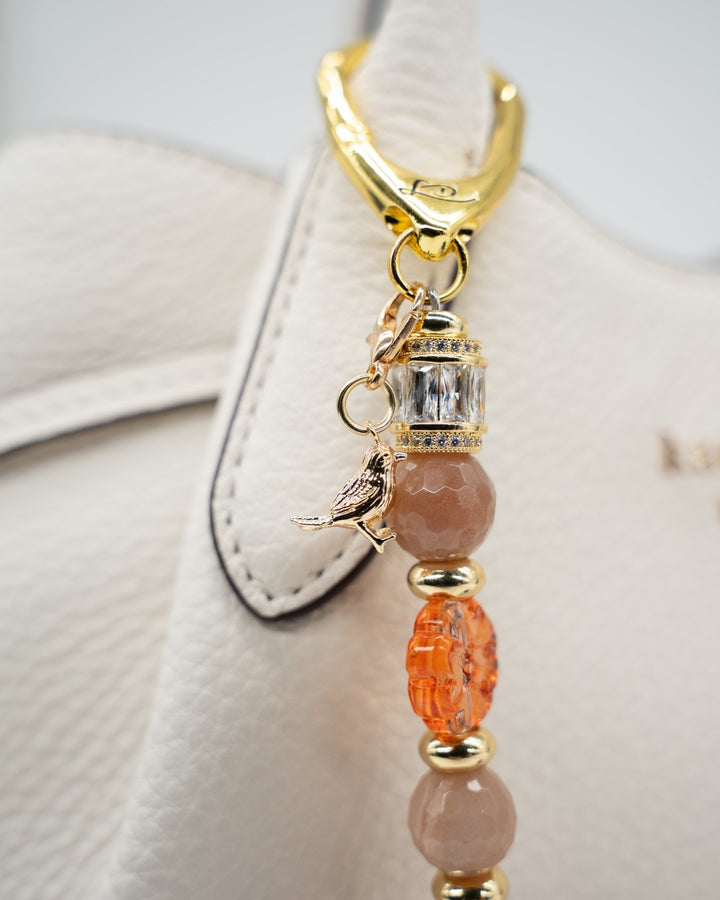 LD Keyfinder Birdsong Bliss featuring sunstone, coral flower beads, and a gold-plated bird charm on a gold clasp.