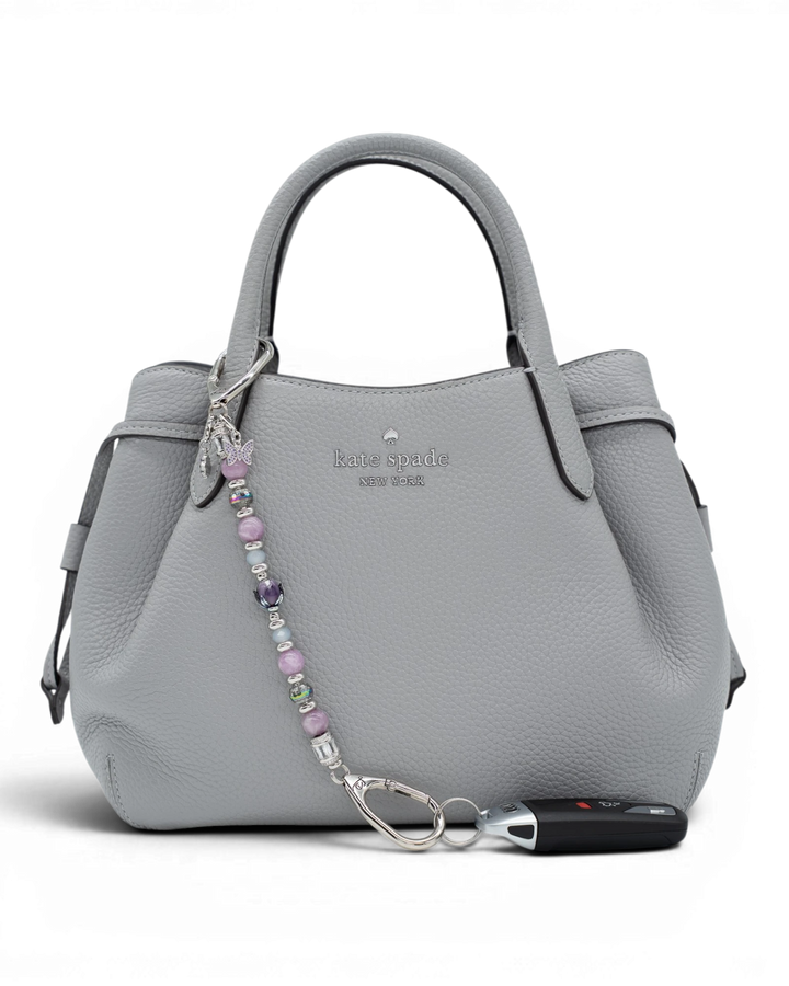 LD Keyfinder Blooming Joy beaded keychain with Lepidolite, Jade, and glass tulip charm attached to a grey leather handbag