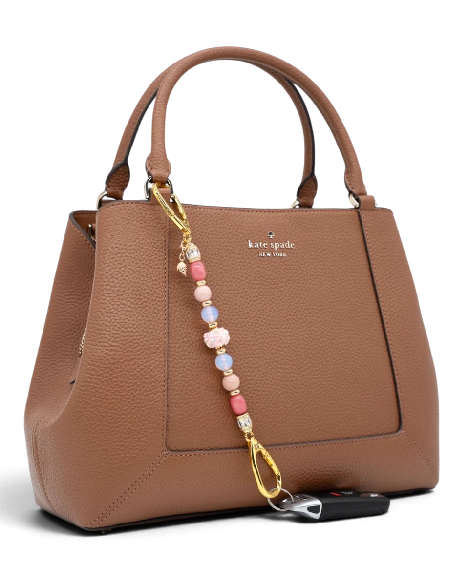 LD Keyfinder Blush Sorbetto beaded accessory with pink gemstones and gold ice cream charm attached to a brown handbag.