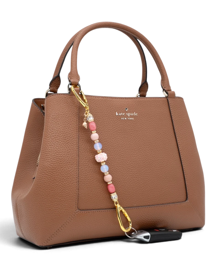 LD Keyfinder Blush Sorbetto beaded accessory with pink gemstones and gold ice cream charm attached to a brown handbag.