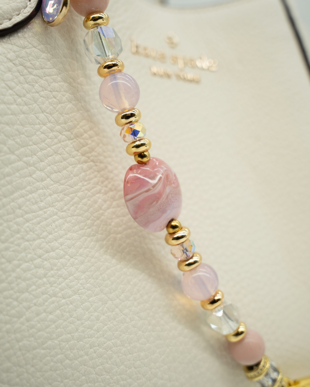 LD Keyfinder Blushing Opaline beaded accessory with pink opal, artisan glass, and 18KT gold accents on a white bag