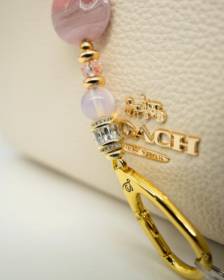 LD Keyfinder Blushing Opaline Petite featuring pink artisan glass, opalite beads, and 18KT gold-plated accents on a bag
