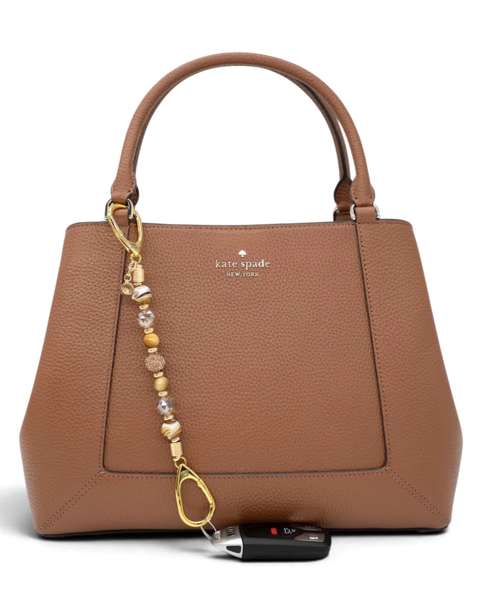 LD Keyfinder Caramel Latte beaded accessory attached to a brown leather handbag with a car key