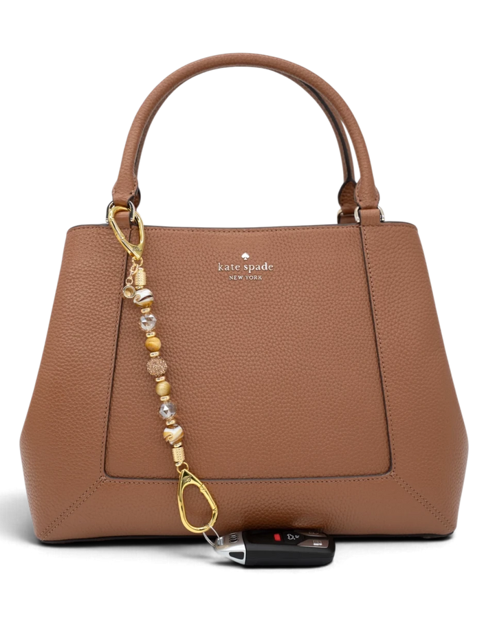 LD Keyfinder Caramel Latte beaded accessory attached to a brown leather handbag with a car key