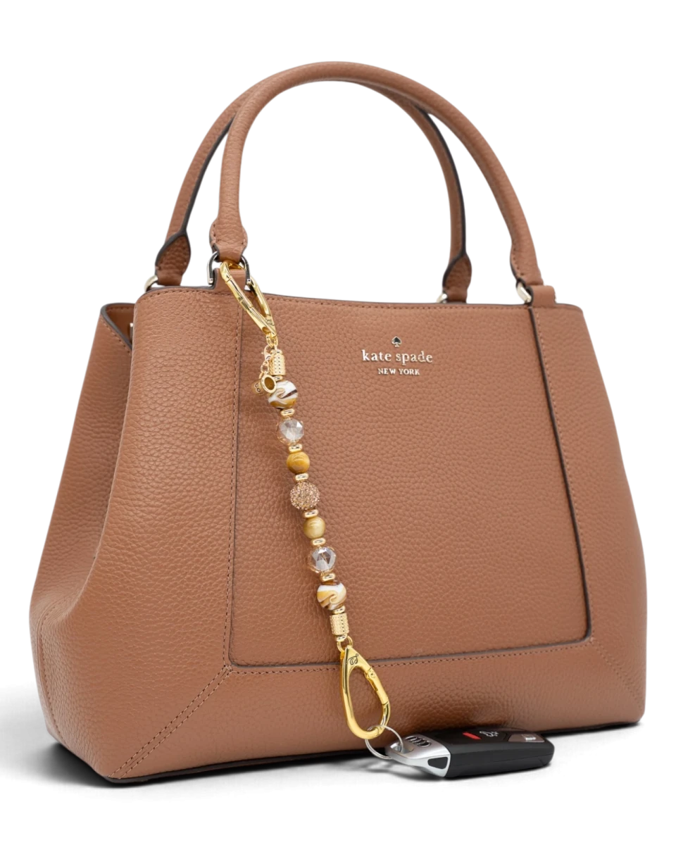 LD Keyfinder Caramel Latte beaded keychain with tiger eye and lampwork glass beads attached to a tan leather handbag.
