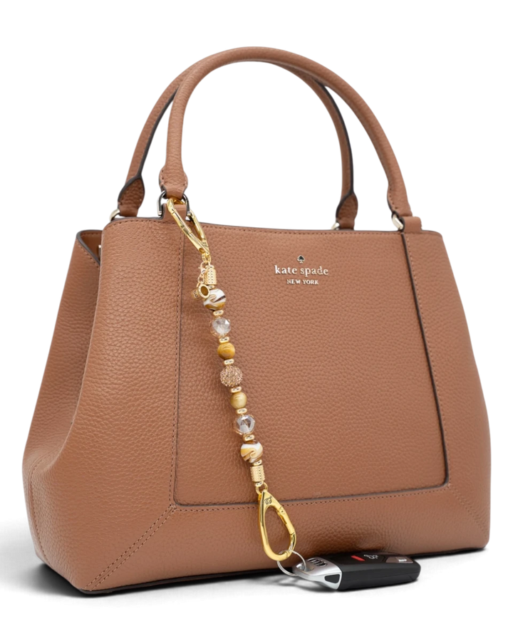 LD Keyfinder Caramel Latte beaded keychain with tiger eye and lampwork glass beads attached to a tan leather handbag.