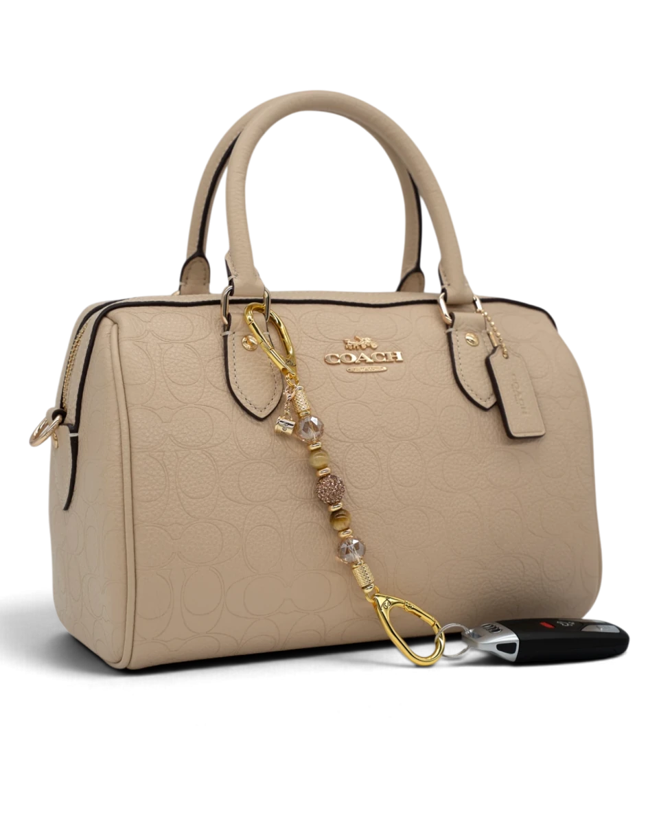 LD Keyfinder Caramel Latte-Mini beaded keychain with Tiger Eye gemstones and gold coffee charm on a beige handbag.