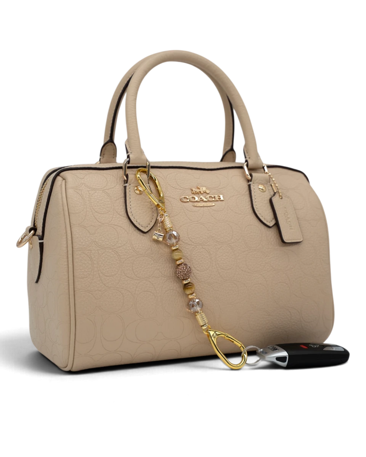 LD Keyfinder Caramel Latte-Mini beaded keychain with Tiger Eye gemstones and gold coffee charm on a beige handbag.