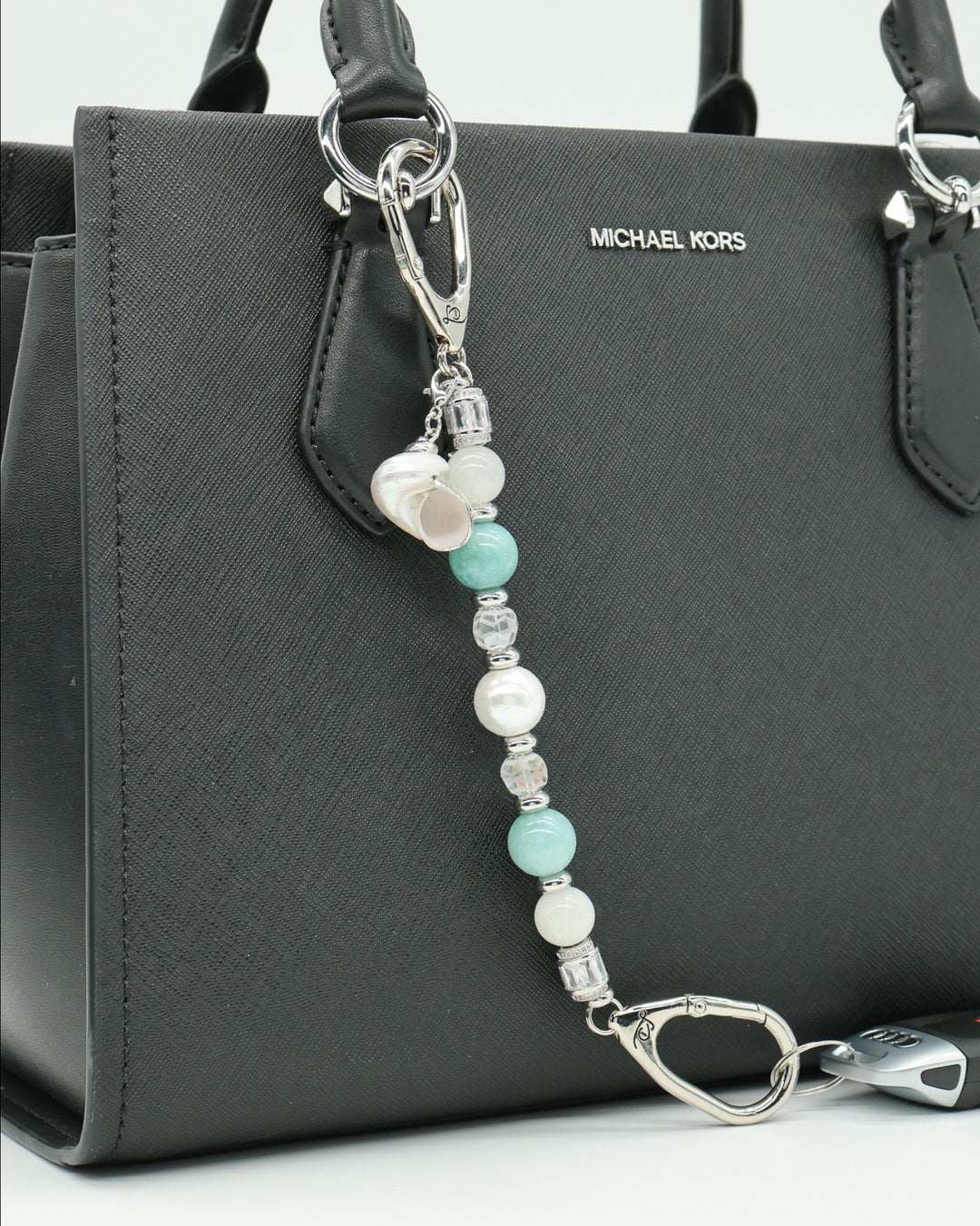 LD Keyfinder Caribbean Pearl beaded accessory with moonstone, aqua jade, and shell pearl charms attached to a black bag.