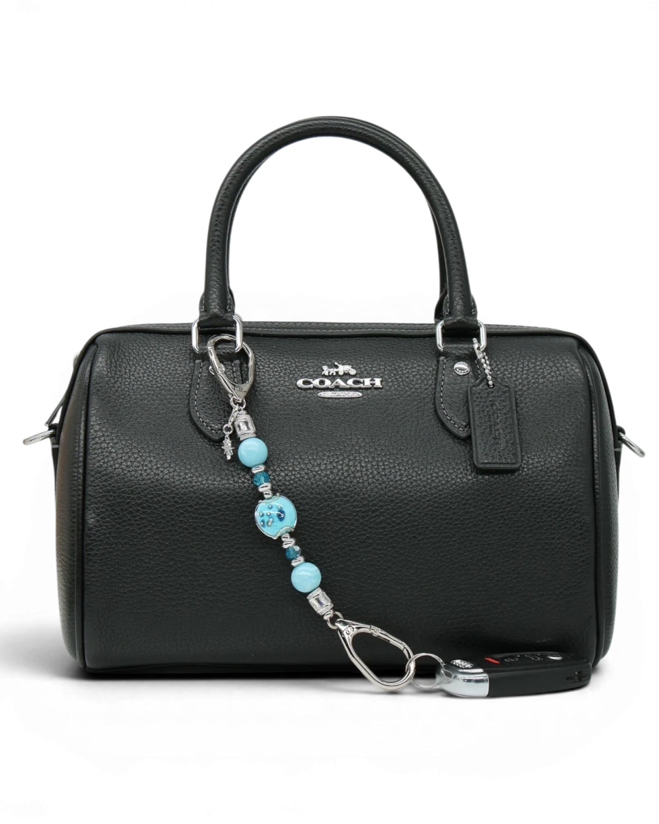 LD Keyfinder Petite Celestial Tide keychain with turquoise, aqua, and silver beads and a star charm attached to a black handbag.