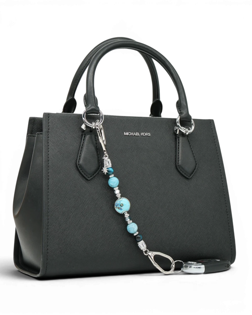LD Keyfinder Celestial Tide keychain with turquoise, aqua, blue tiger eye, larimar beads, and silver star charm on black handbag.