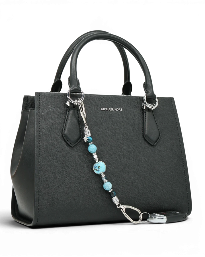 LD Keyfinder Celestial Tide keychain with turquoise, aqua, blue tiger eye, larimar beads, and silver star charm on black handbag.