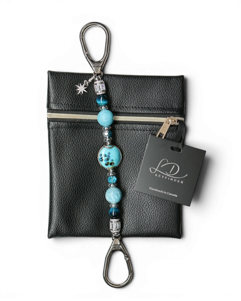 LD Keyfinder Celestial Tide keychain with turquoise glass bead, blue tiger eye, larimar, and silver accents, attached to a black pouch.