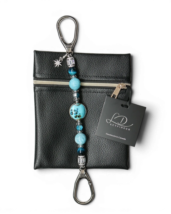 LD Keyfinder Celestial Tide keychain with turquoise glass bead, blue tiger eye, larimar, and silver accents, attached to a black pouch.