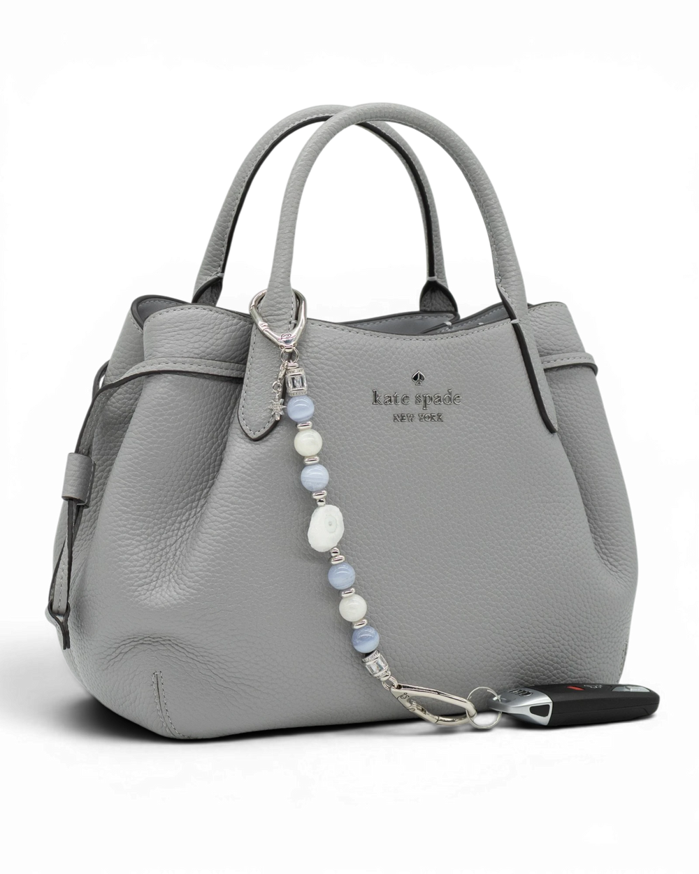 LD Keyfinder Cloud Dancer accessory with blue lace agate and moonstone beads attached to a grey leather handbag.
