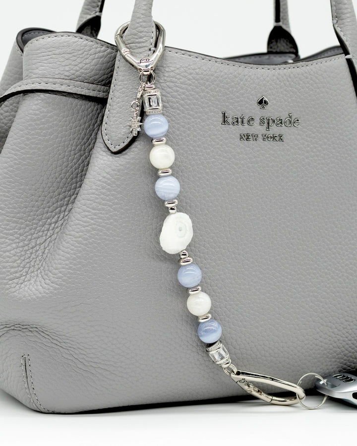 LD Keyfinder Cloud Dancer accessory with blue lace agate, moonstone, and a star charm attached to a grey handbag.