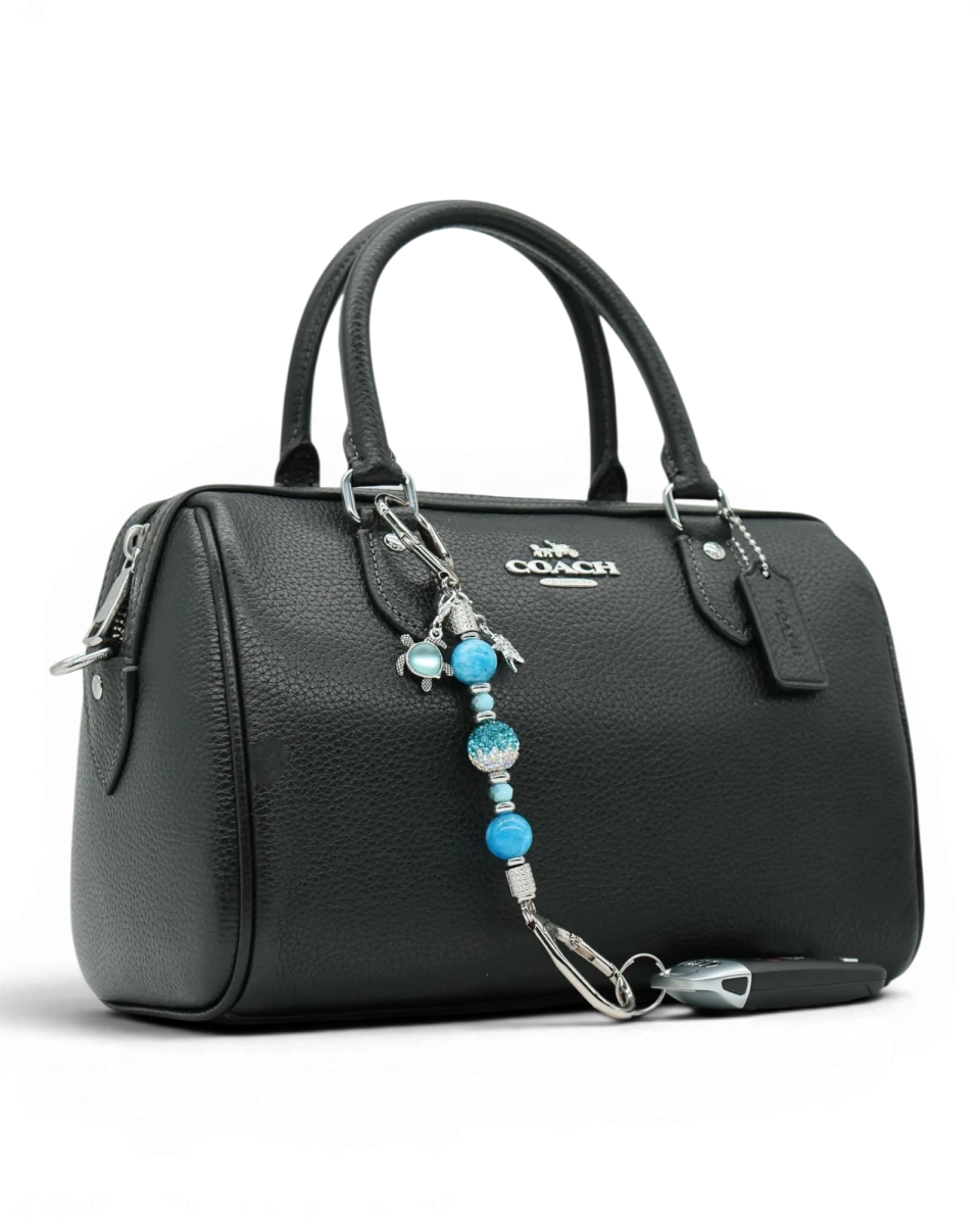 LD Keyfinder Coastal Tide Mini keychain with blue gemstone beads, turtle and starfish charms attached to a black handbag.
