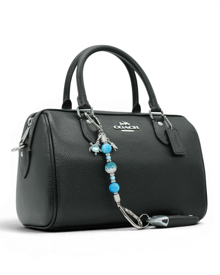LD Keyfinder Coastal Tide Mini keychain with blue gemstone beads, turtle and starfish charms attached to a black handbag.