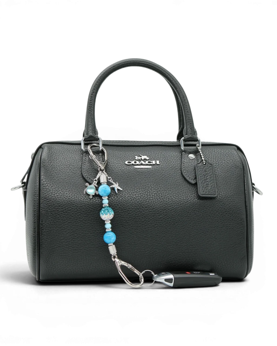 LD Keyfinder Coastal Tide Mini keychain with blue gemstone beads, crystal bead, turtle and starfish charms attached to a black handbag.