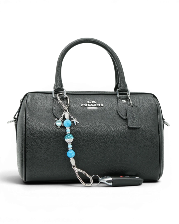 LD Keyfinder Coastal Tide Mini keychain with blue gemstone beads, crystal bead, turtle and starfish charms attached to a black handbag.