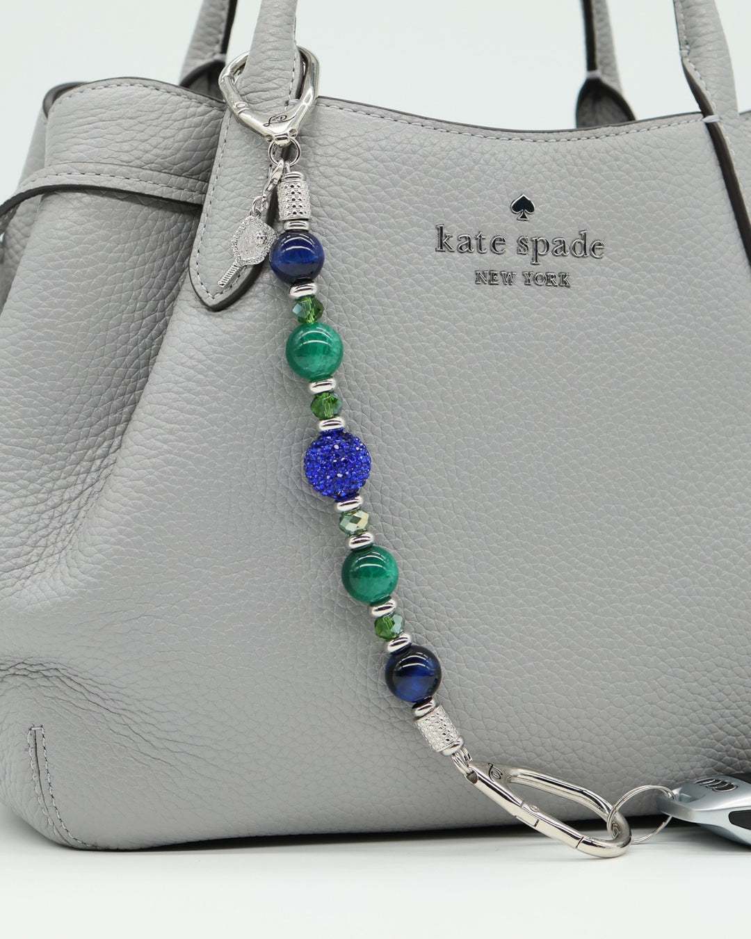 LD Keyfinder Courtside Bliss pickleball bag charm with blue tiger eye, green agate, and crystal beads on a grey bag.